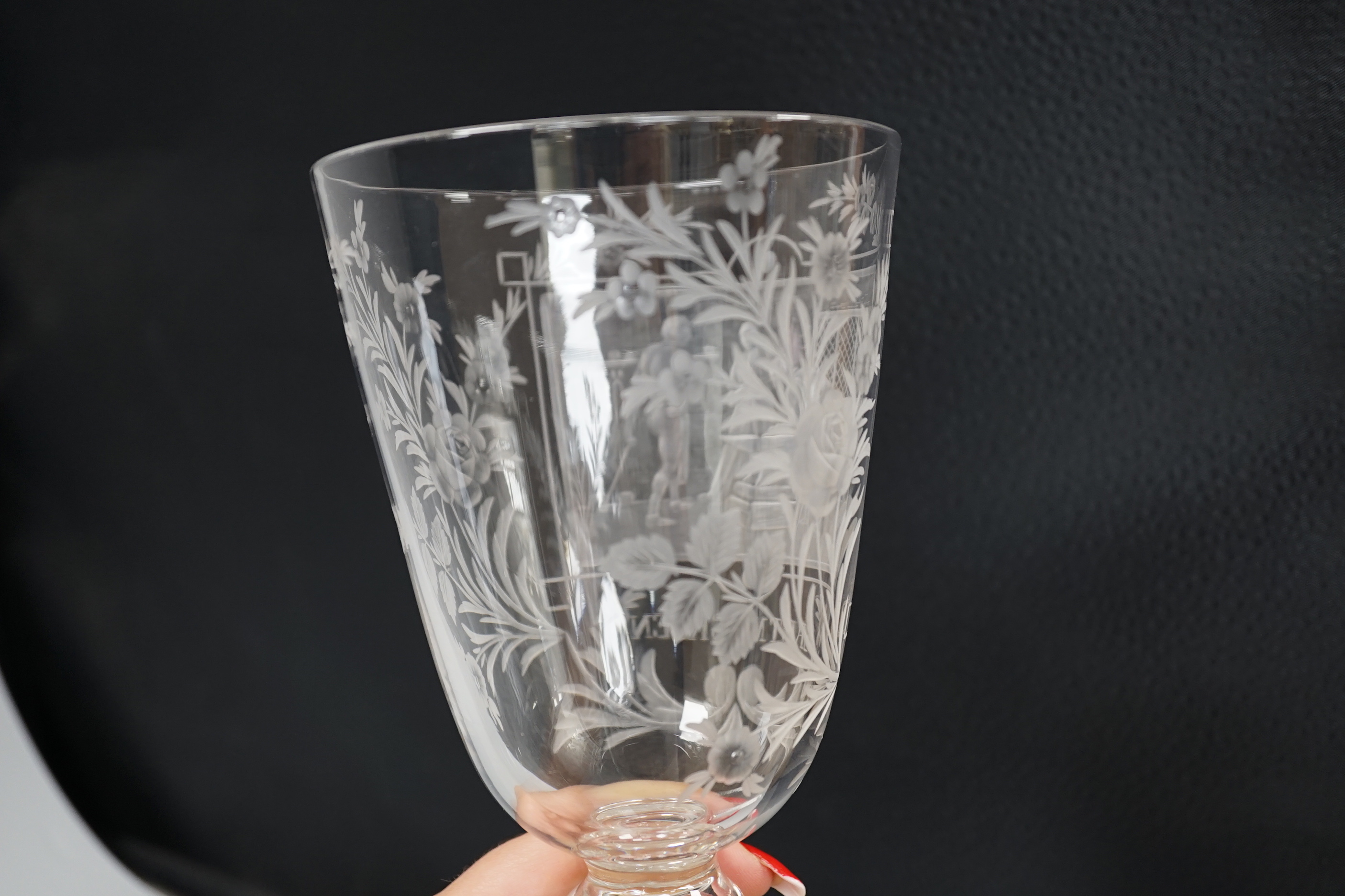 A lead crystal commemorative Gretna Green goblet, with fine engraving of a blacksmith and couple signing the register on an anvil, the panel surrounded by floral engraving, ‘GRETNA GREEN’ below, 23.9cm high